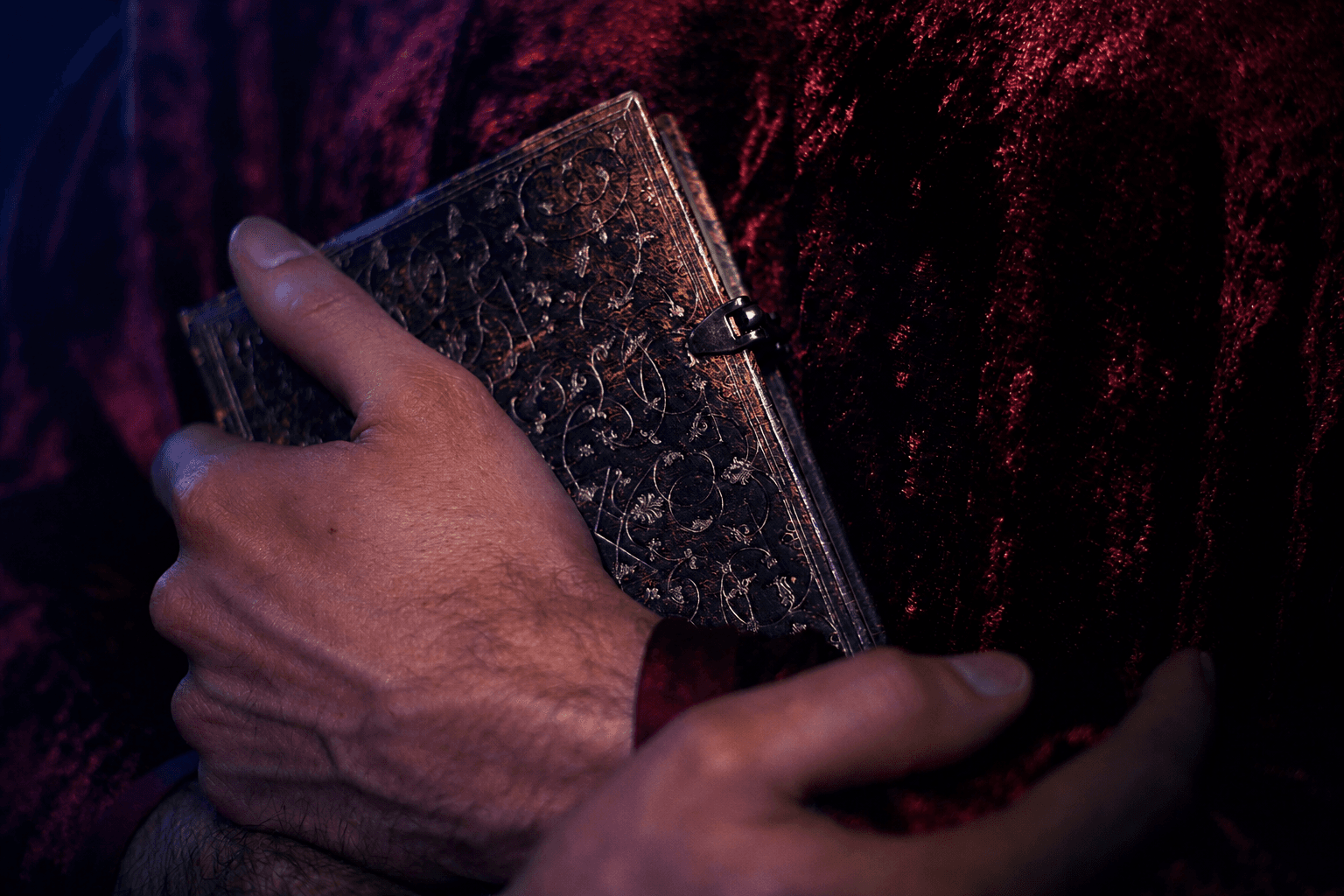 Main tenant un livre ancien avec une couverture en cuir sculptée